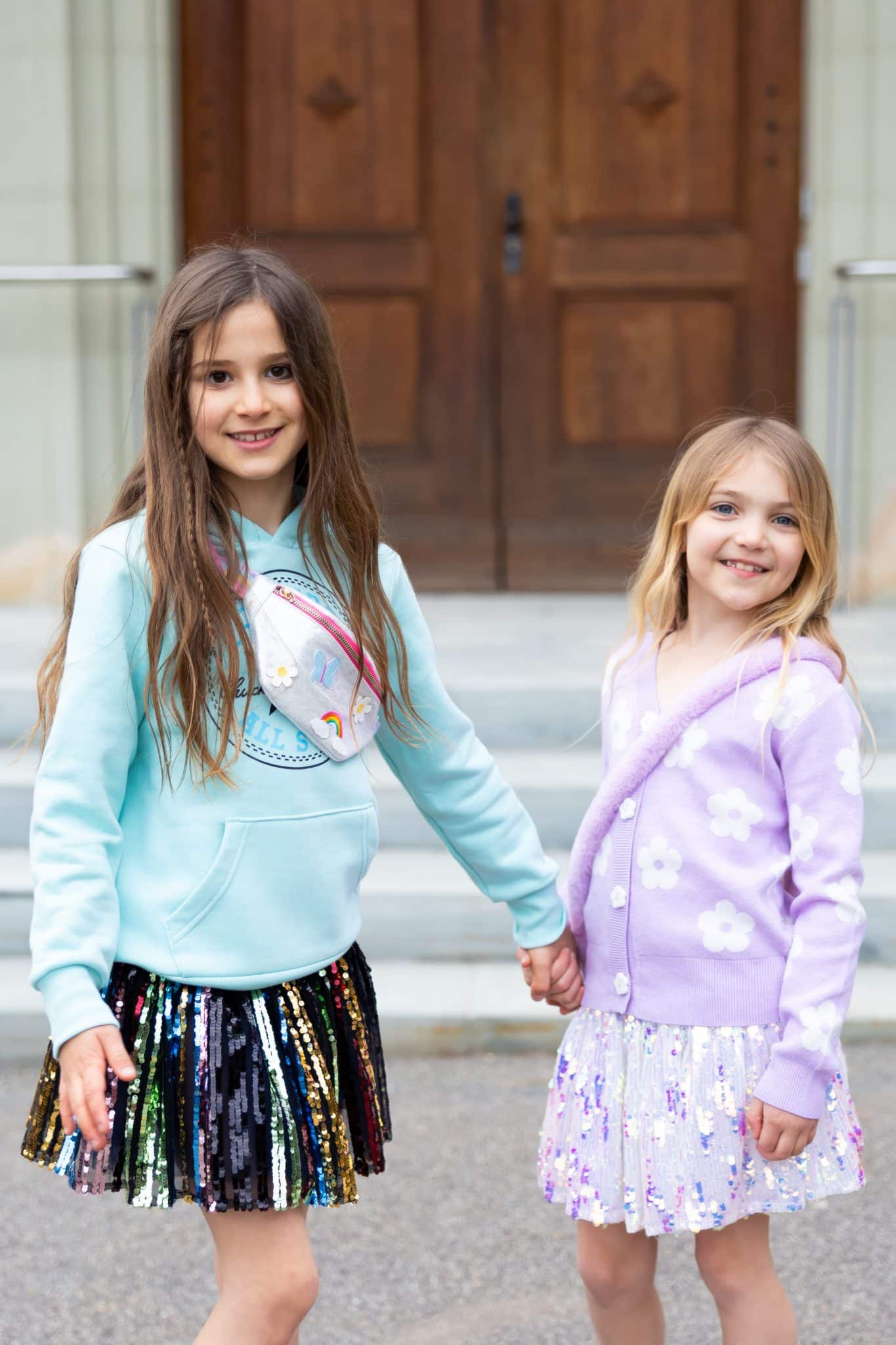 Regenboog Unicorn schoudertas voor een kind: tasje kind met rits, gedragen door een meisje naast een ander meisje.