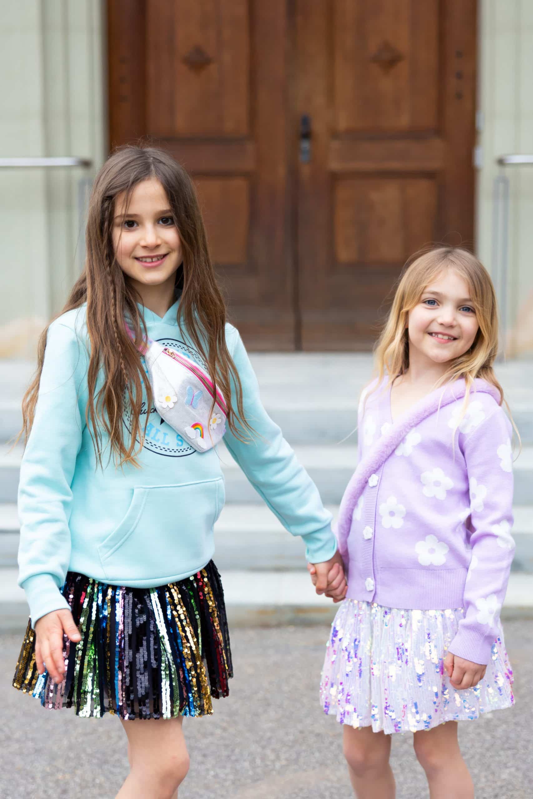 Regenboog Unicorn schoudertas voor een kind: tasje kind met rits, gedragen door een meisje naast een ander meisje.