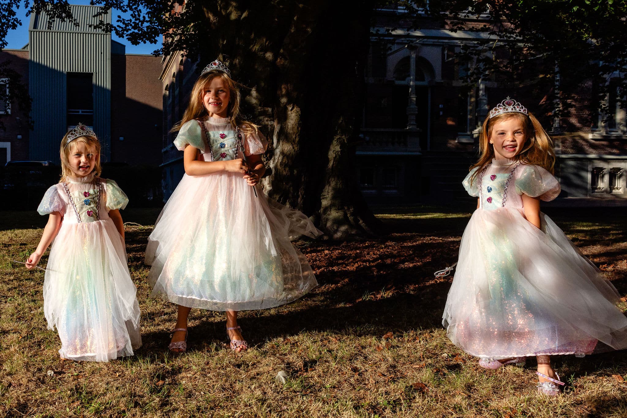 Drie meisjes dragen een regenboog prinsessenjurk kind met glanzende pastelrok en kroon in een park