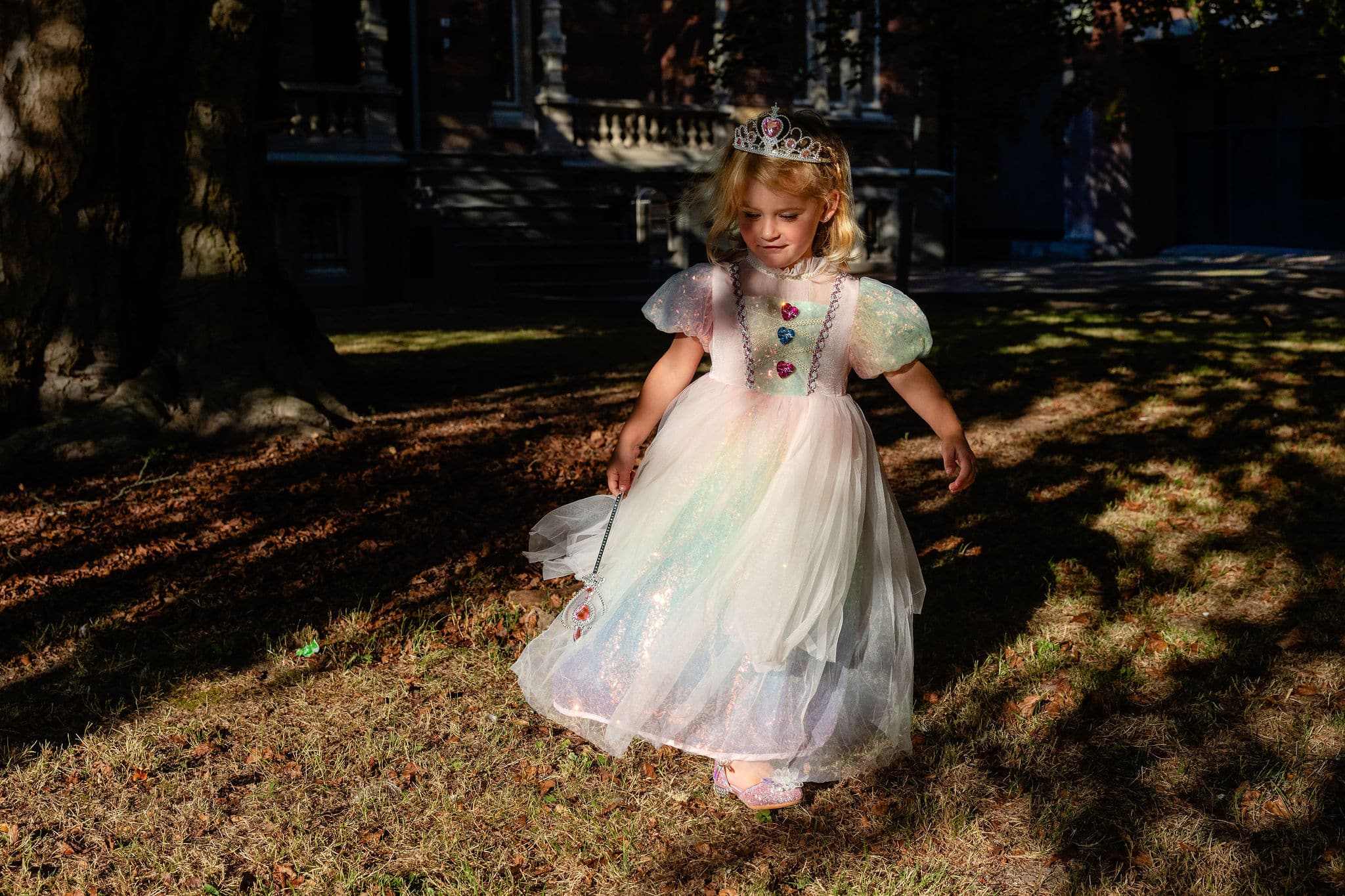 Prinsessenjurk meisje in regenboogkleuren, met kroon en glanzende rok in een park